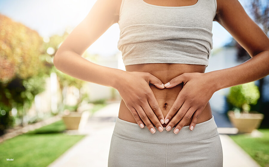 Model has her hands on her stomach in a park